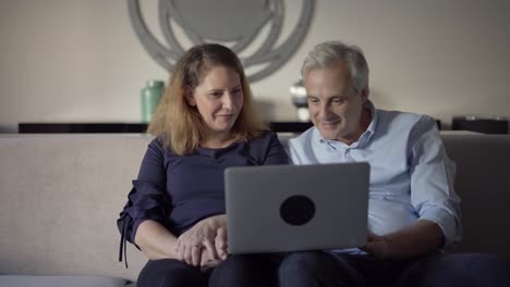 Positive-mid-adult-couple-using-laptop-for-video-call